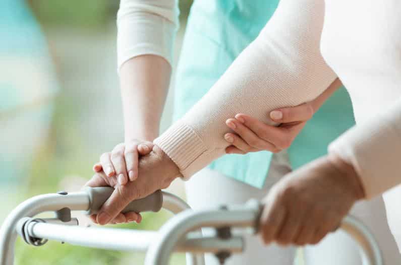 Someone helping a person use a walker